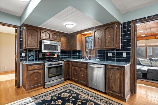 Spacious eat-in kitchen featuring rich wood cabinetry, stainless steel appliances, generous storage, granite counter-tops & hardwood floors. The open layout flows beautifully into the surrounding living spaces.