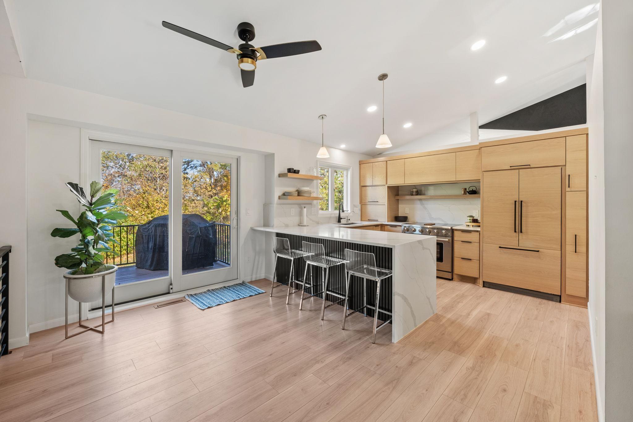 Open and airy modern kitchen, complete with waterfall quartz countertops, custom white oak cabinetry and walk out to the expansive deck.