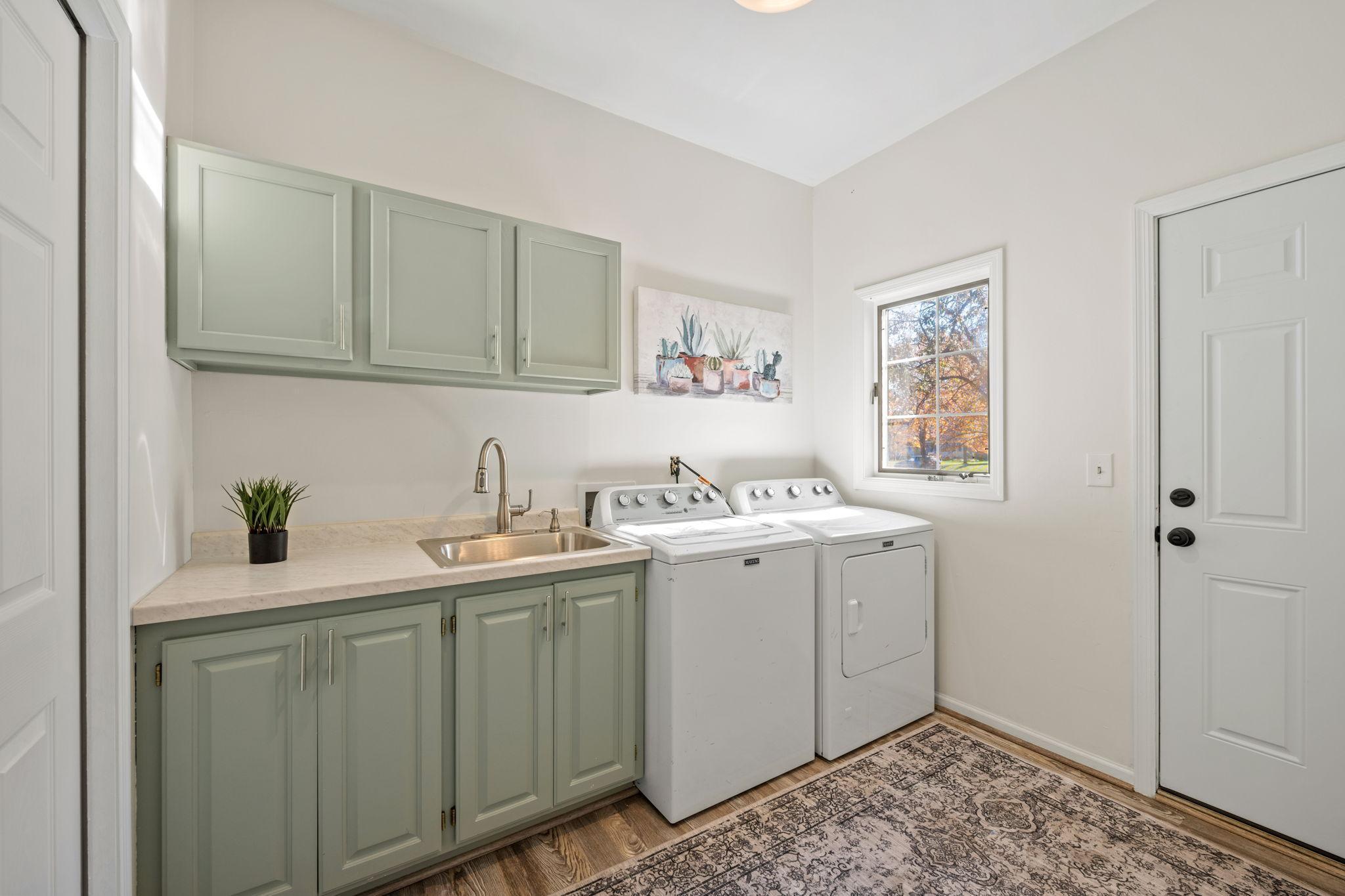 Large laundry room has built in custom cabinetry and sink.