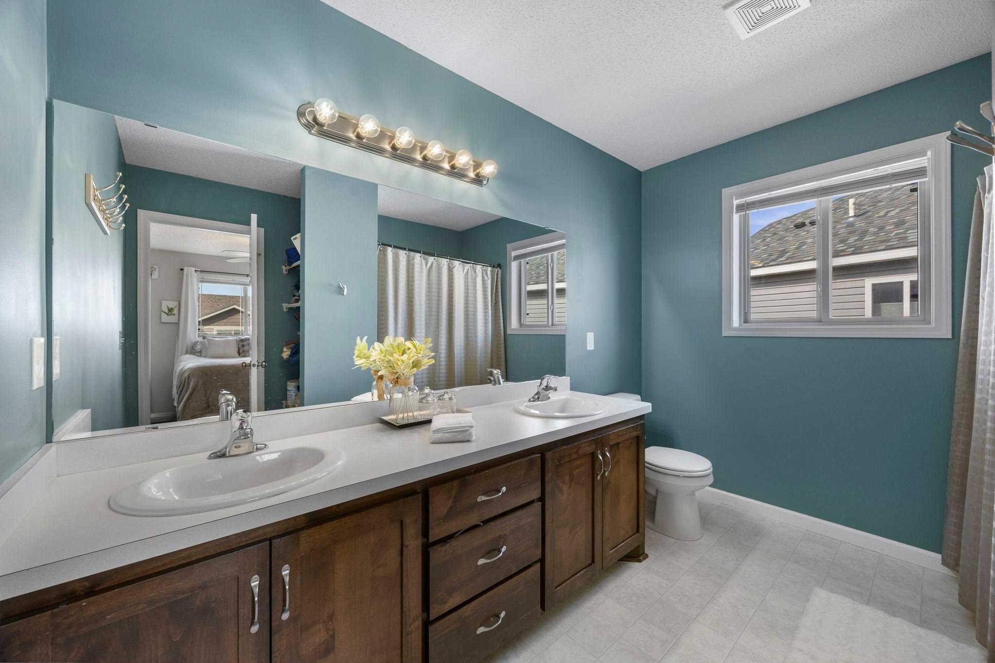 Primary bath features doubles sinks and rich wood cabinetry