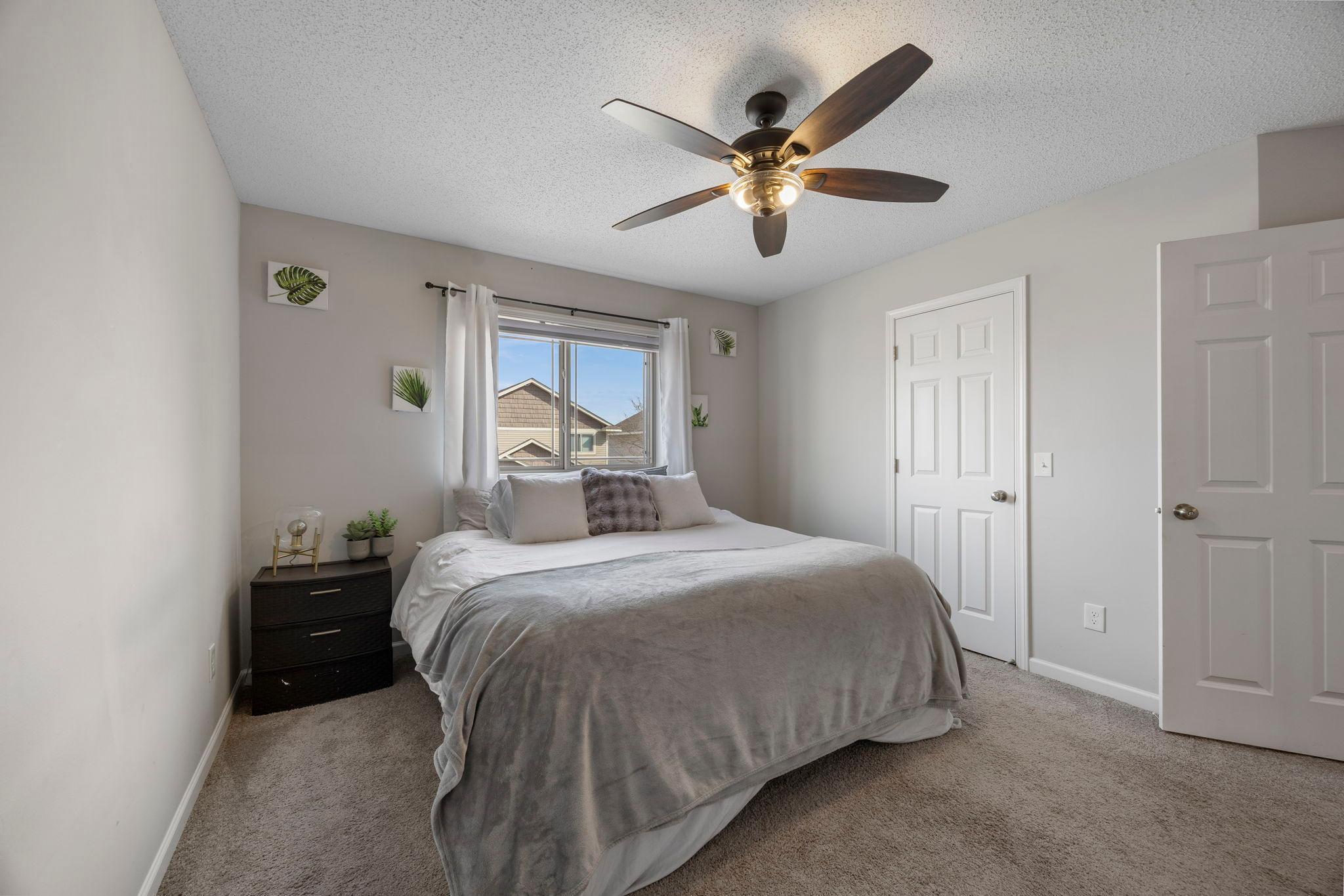 Upper level primary bedroom includes ceiling fan and a walk-in closet