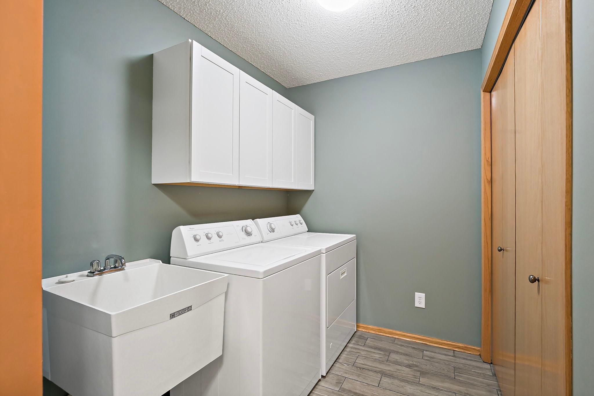 Amazing-sized laundry room featuring a hard-to-find sink, extra-deep storage area, and added cabinet storage above the washer and dryer
