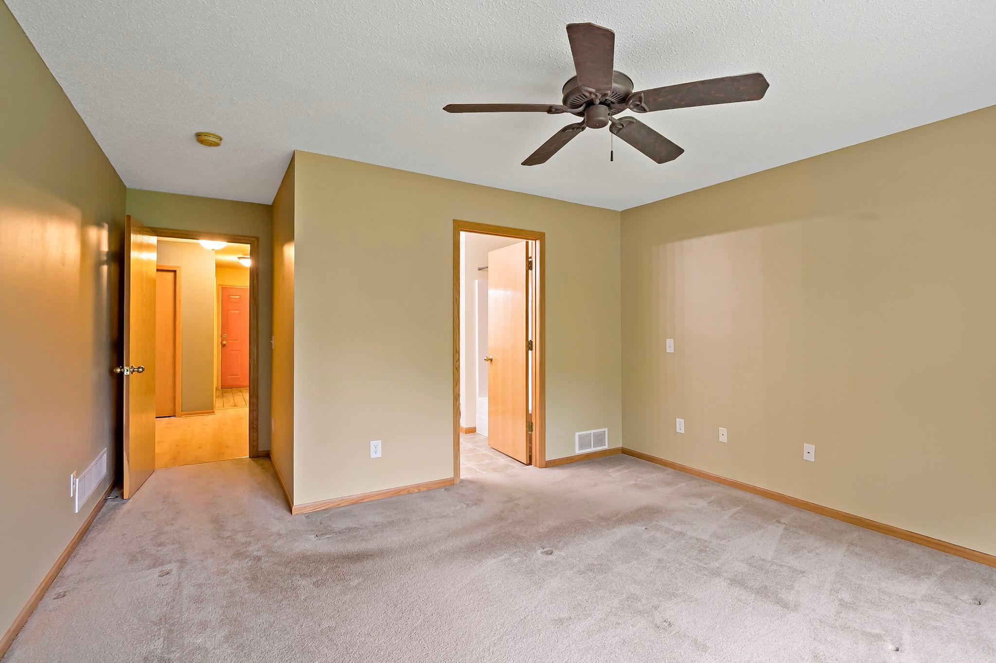 A spacious, unstaged owner’s suite showcasing impressive room size and natural light, with a convenient walk-through layout leading directly to an oversized closet