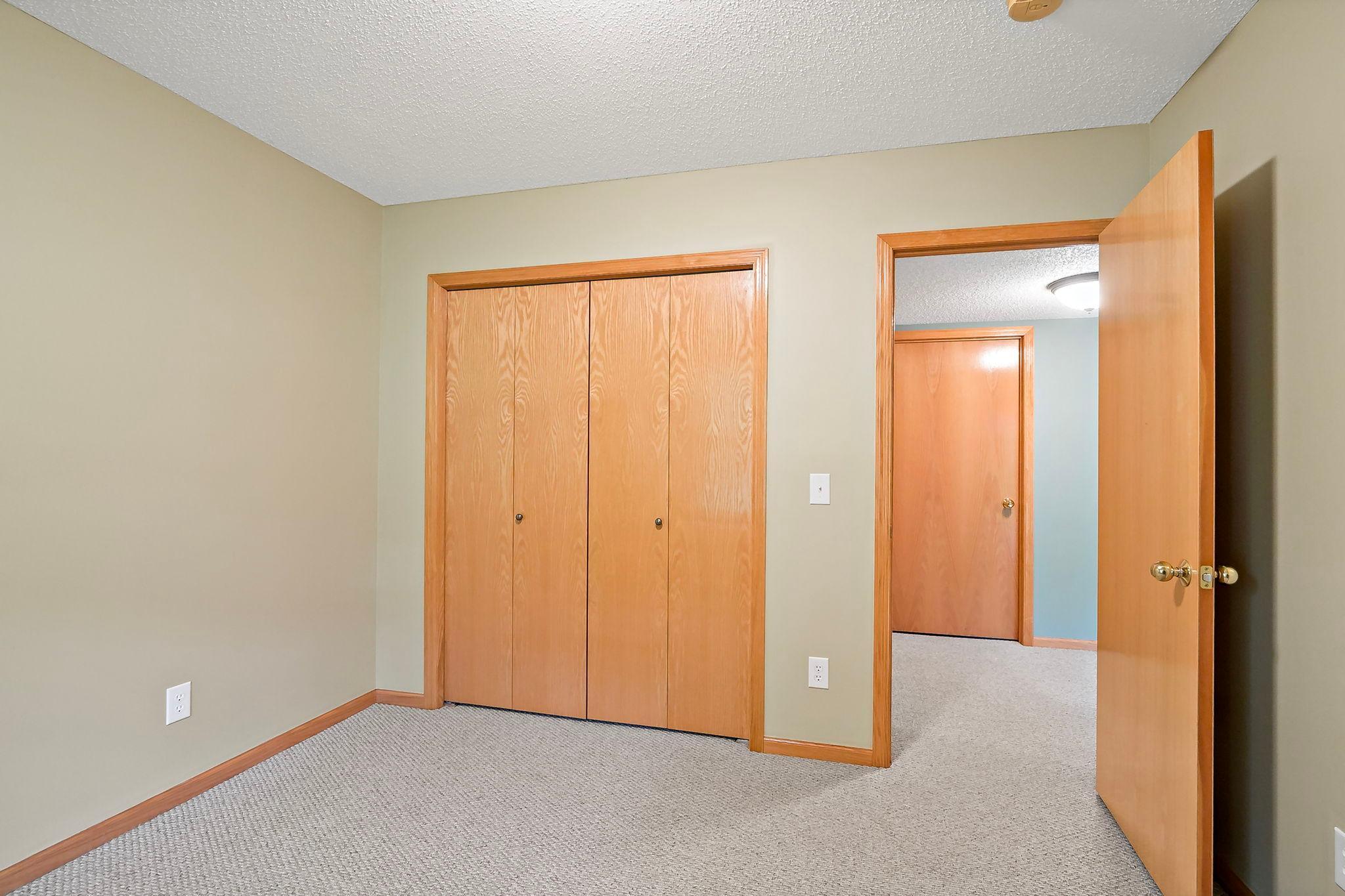 Third lower-level bedroom, currently unstaged, showcasing its clean slate, generous space, and versatility to be customized to your needs. At oppsite side of the 2nd bedroom.