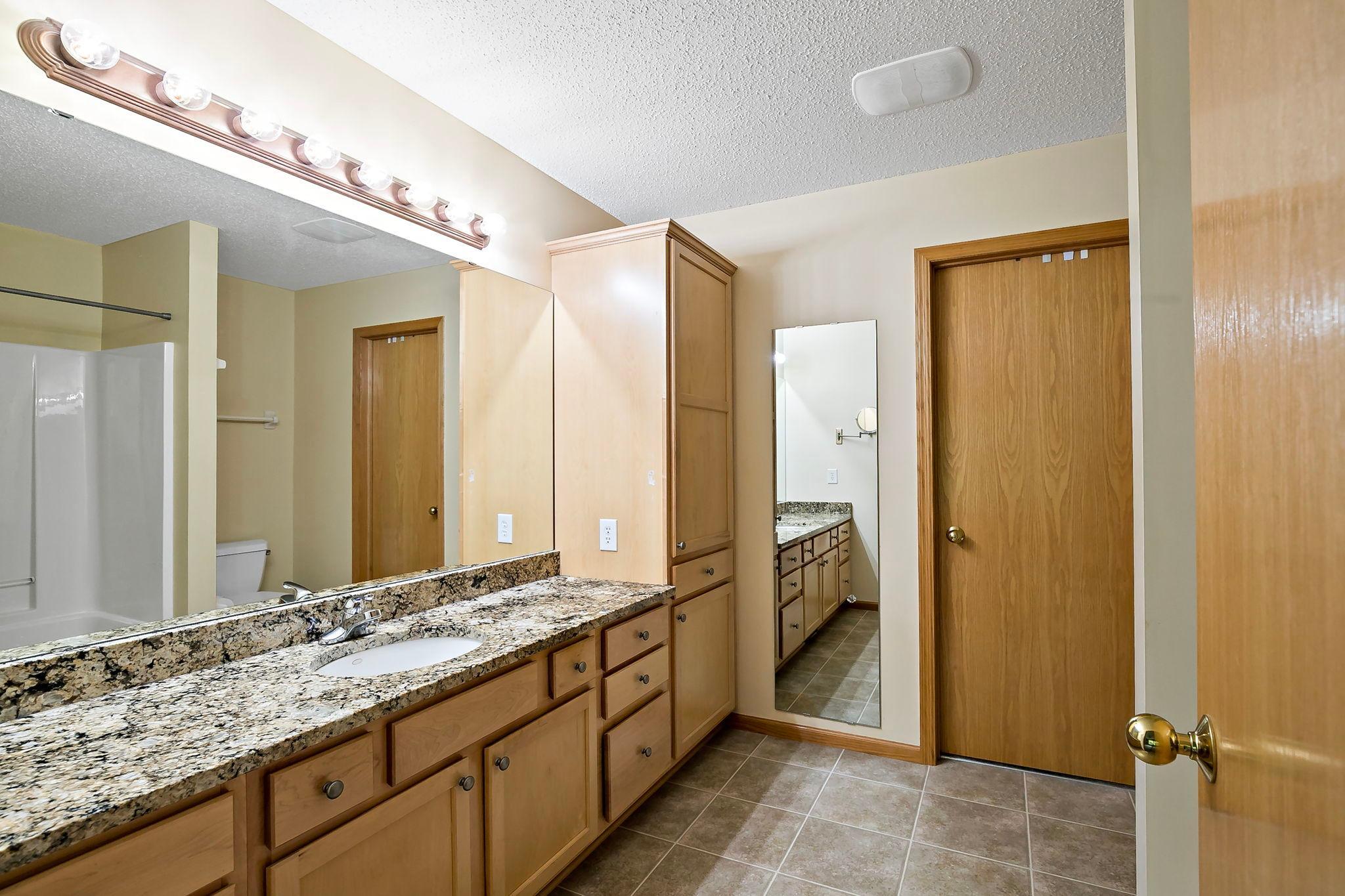 A full owner’s bath with a wide, open layout and extra built-in storage, designed for everyday convenience, seamlessly flowing into a massive walk-in closet for exceptional space and functionality.