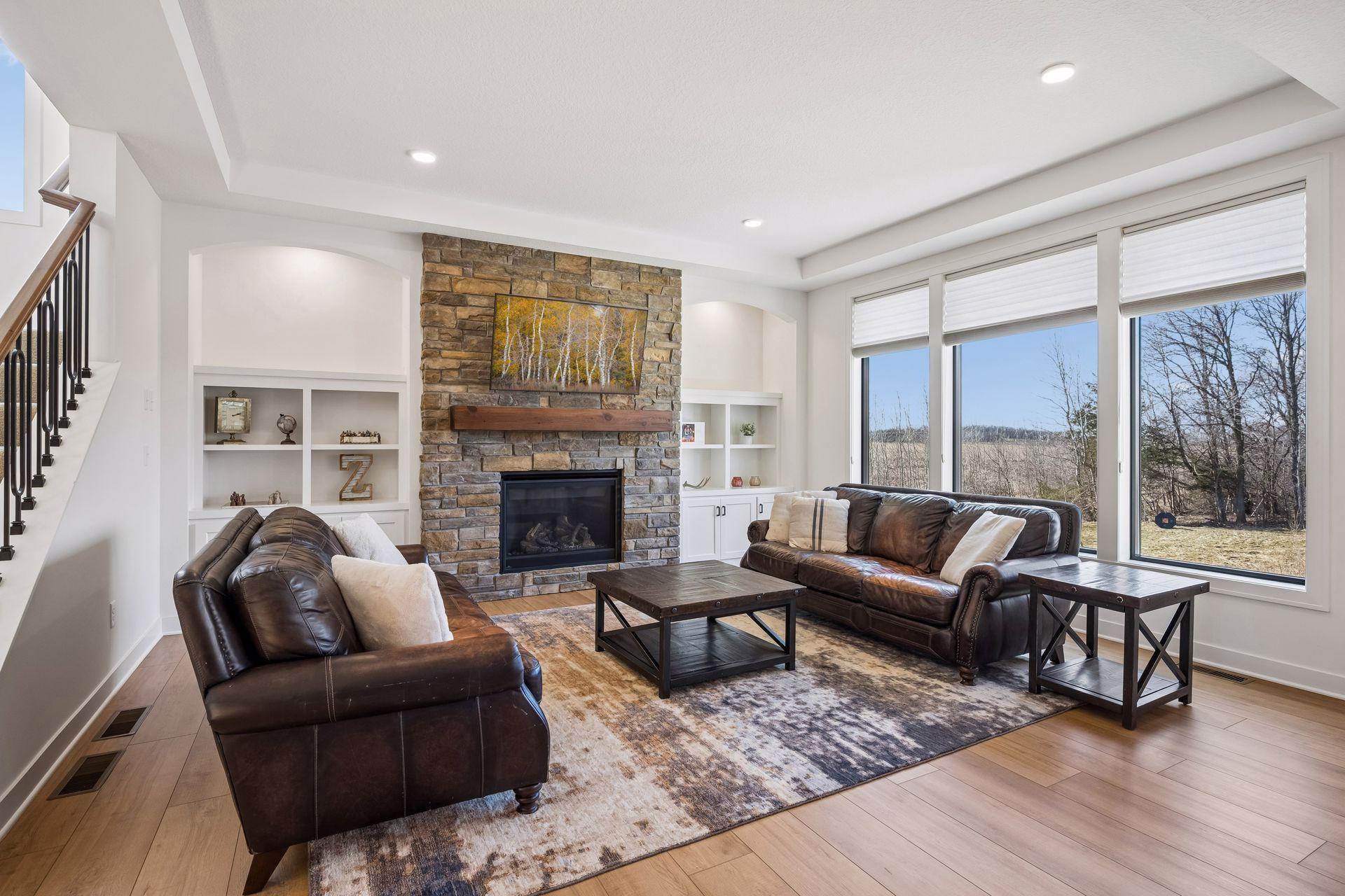 Great room with stone floor to ceiling fireplace, large windows, and trace ceiling.