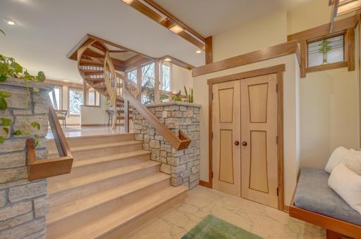 The welcoming foyer includes a bench, coat closet, heated stone floor, and a half bath.