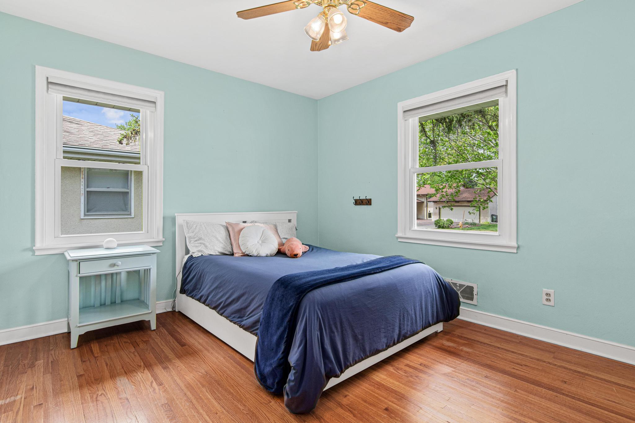 Bedroom 3 of 3 on the main floor has hardwood floors, a large closet, updated windows and a ceiling fan. The paint color is a beautiful Tiffany blue.