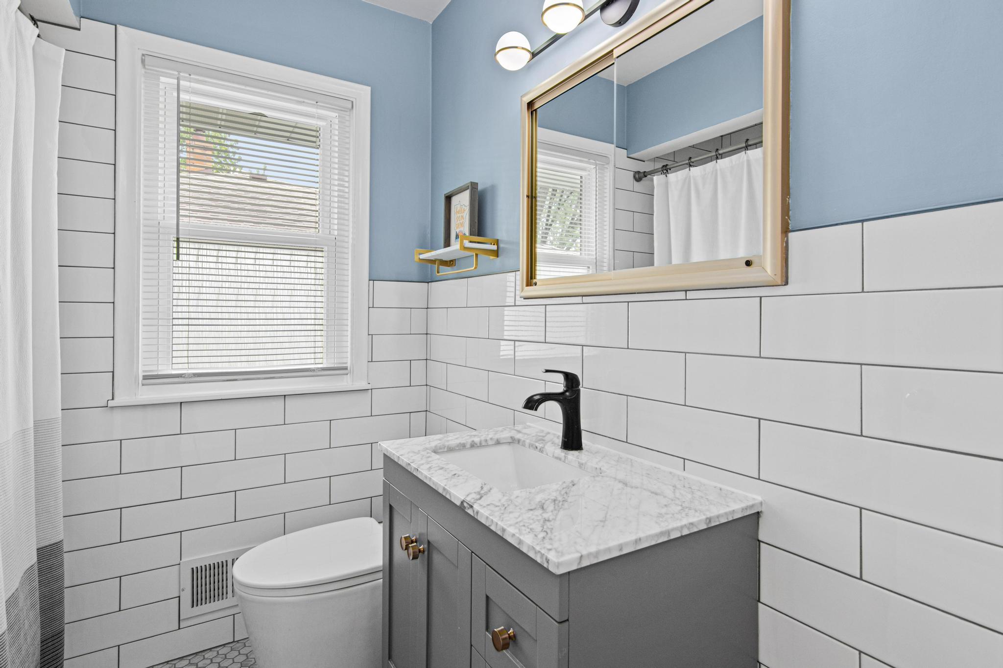 The main floor bathroom was completely remodeled in 2024 and now features gorgeous elongated subway tile, an updated vanity, easy to clean commode, and on trend lighting.