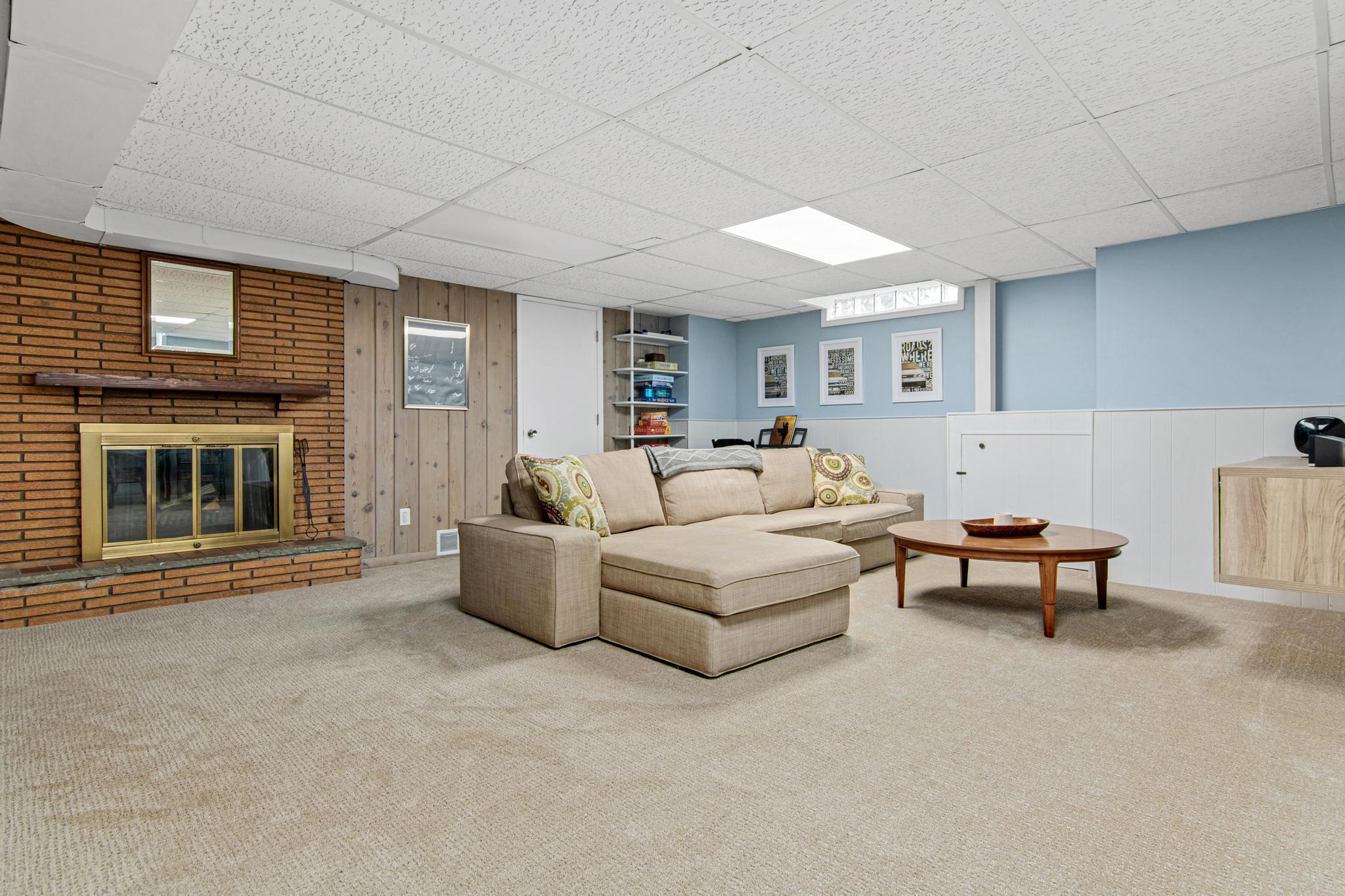 The lower level family room is sure to be a favorite hang out space for the entire family. The original wood burning fireplace brings mid-century flare. This space has brand new carpet too!
