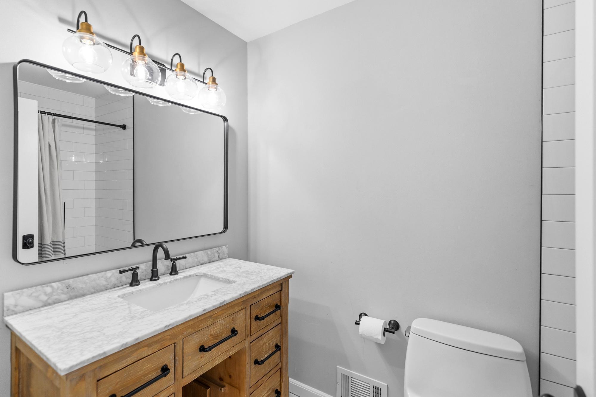 Just down the hall from the main living spaces is the first of three fully renovated bathrooms. This full bath serves the two secondary bedrooms on this floor.