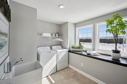 (Photo of model home, features will vary) The laundry room features a brand-new washer and dryer, sink, a countertop for folding, cabinetry storage and shelving.