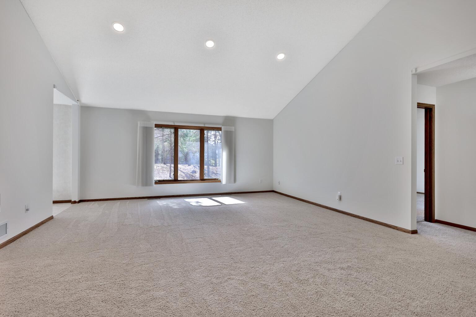 Spacious living room with vaulted ceiling and large bright windows