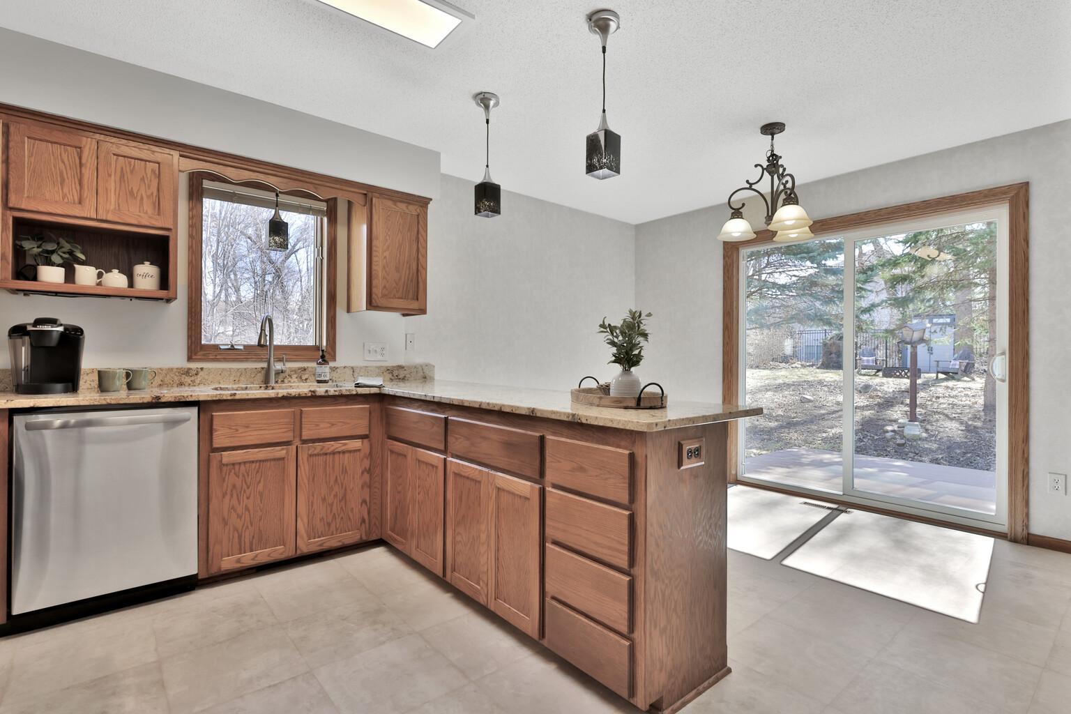 Kitchen toward dining. Newer patio door leading to maintenance free deck in private backyard.