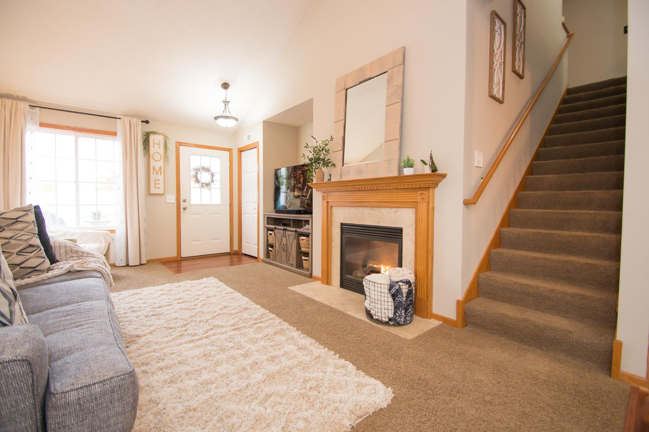 Bright living room with vaulted ceilings, large windows, and a cozy gas fireplace