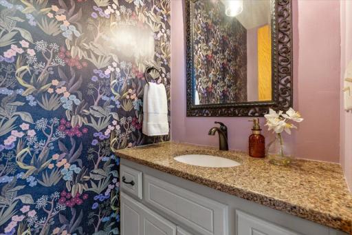 Guest half bath that woke up and chose drama - in the best way with floral wallpaper and granite countertop.