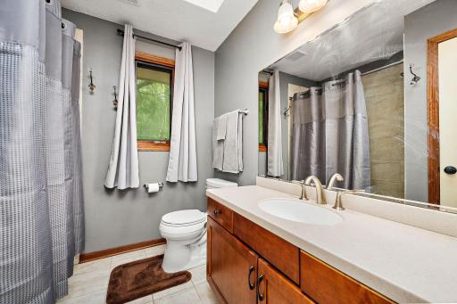 The upper-level full bathroom is filled with natural light thanks to a window and skylight.