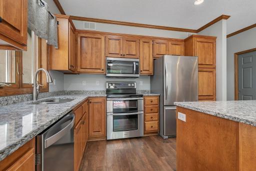 The kitchen boasts updates galore, including custom-built cabinetry, brilliant granite countertops, a central island, and modern stainless steel appliances.