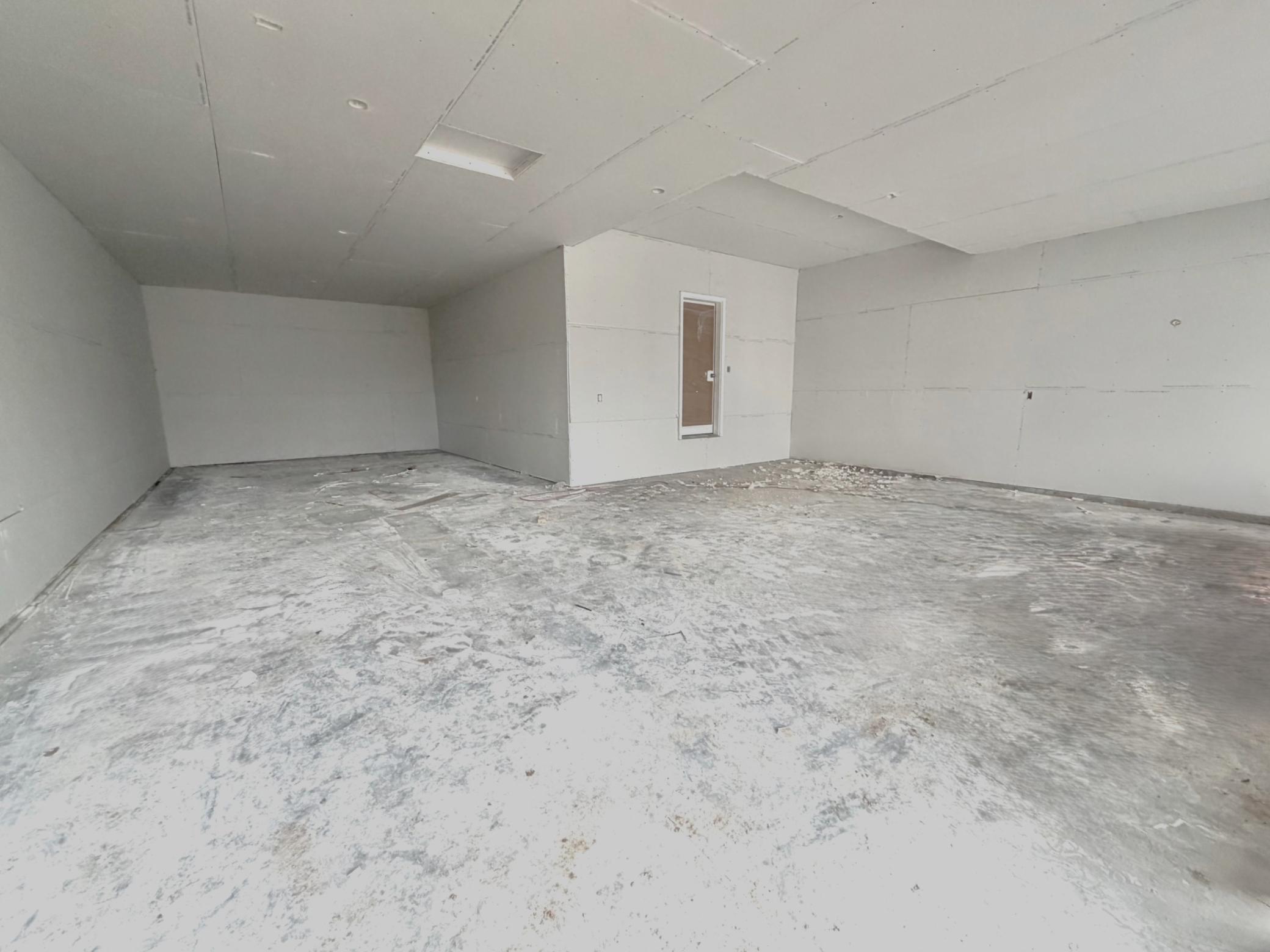 3199 Jandura Ave NE- Photo of actual home under construction. Spacious 4 Bay Garage offering great storage and room for work area too! Please excuse the sheetrock dust on the garage floor. Stairs will be installed at the garage/entry door soon.