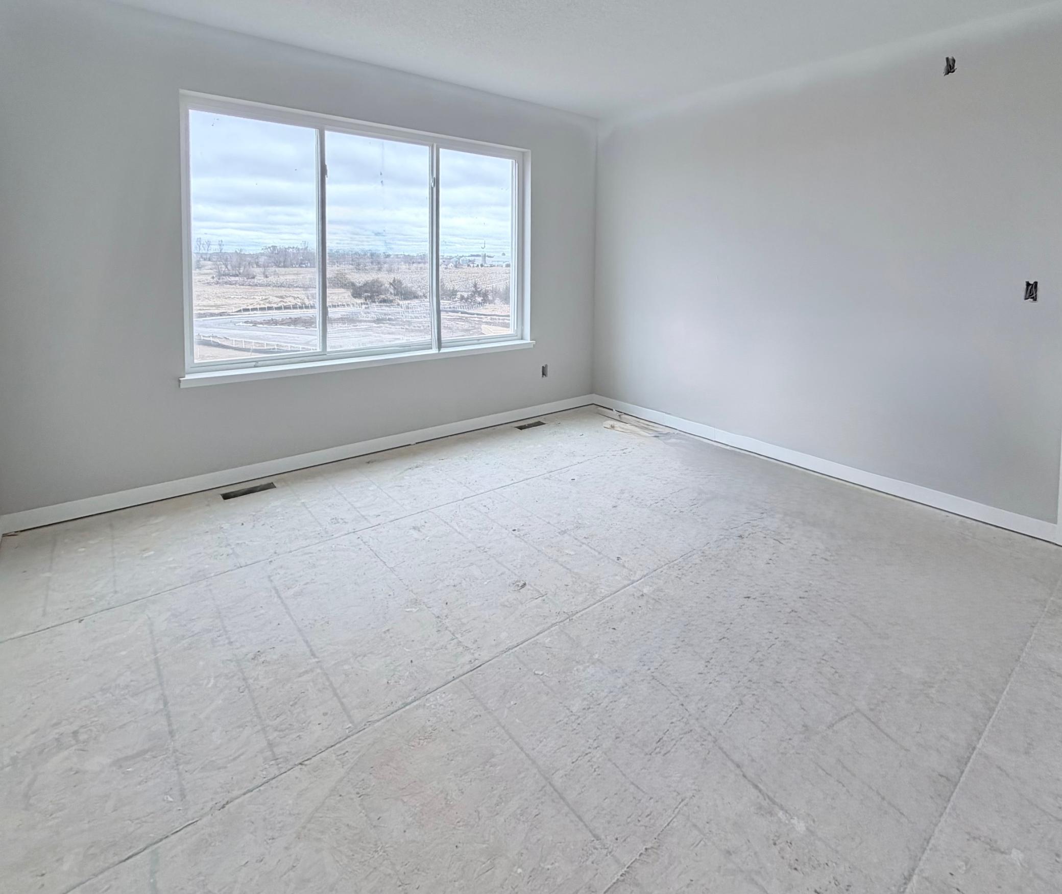 3199 Jandura Ave NE- Photo of actual home. Primary Suite features a large window with backyard views, walk-in closet, and private bathroom.