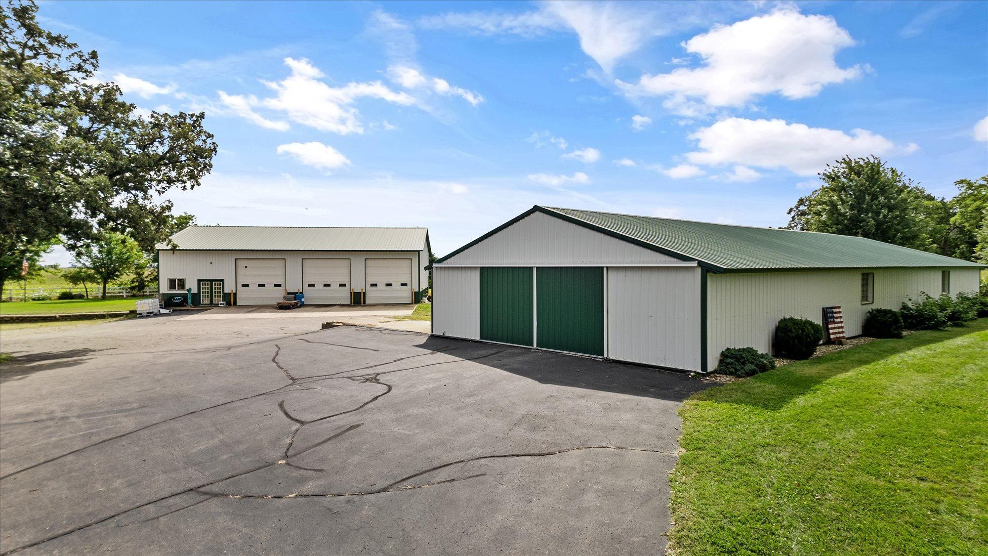 98x33 Barn w/ Green Doors & Roof: foreground. 64x40 Heated Shop w/Office & drive in doors in background.