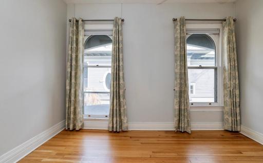 The fourth bedroom also features stunning windows and gleaming hardwood floors.