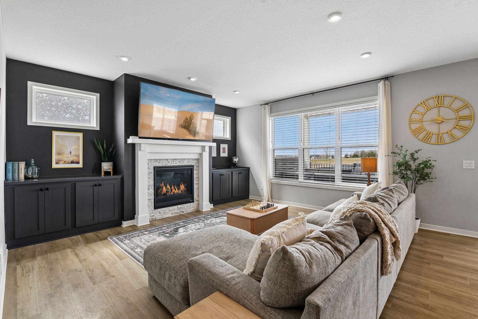 This living room makes a statement the second you walk in. Floor-to-ceiling dark accent built-ins, a fireplace that anchors the whole space, and windows that flood the room with natural light.