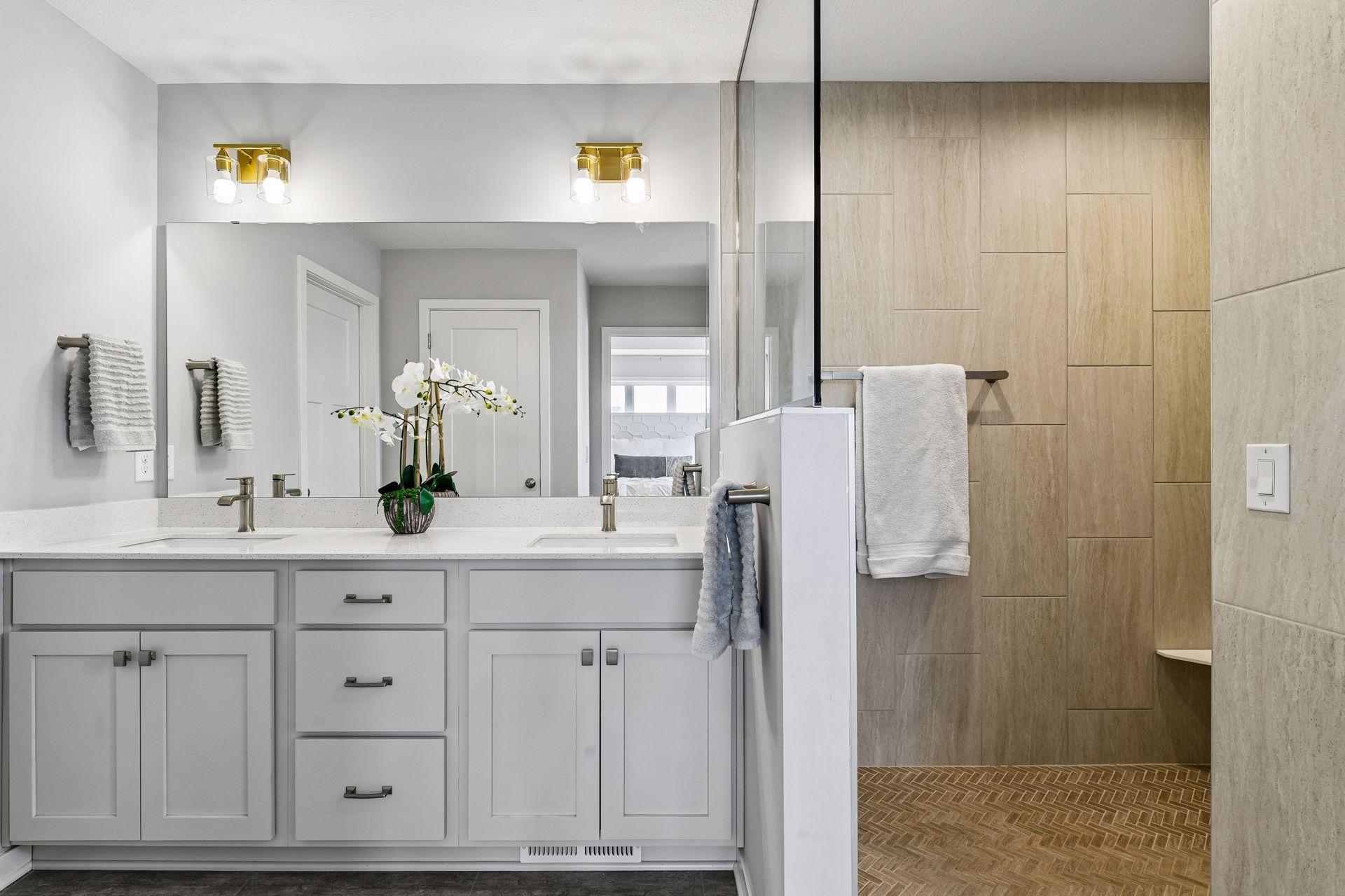 Primary bathroom has dual vanities, tiled walk in shower and large walk in closet