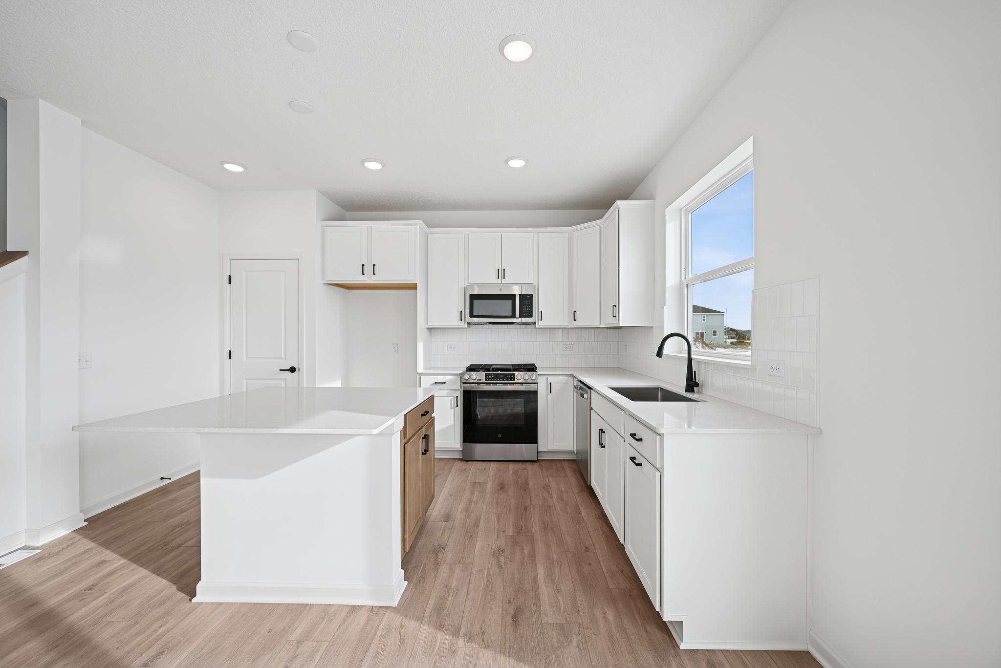 The chef-inspired kitchen serves as the heart of the home, featuring a dine-up island, abundant storage, and ample prep space. **Photo of similar home**