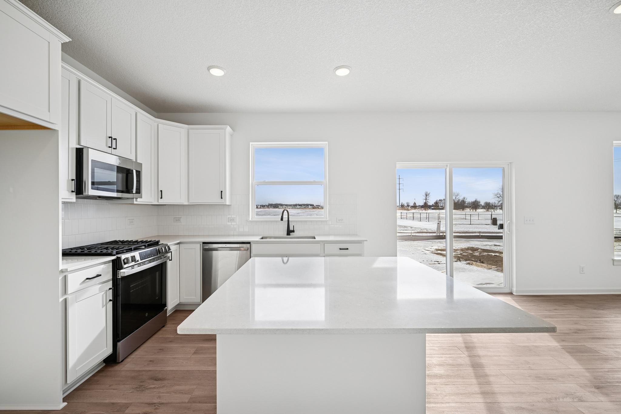 The chef-inspired kitchen serves as the heart of the home, featuring a dine-up island, abundant storage, and ample prep space. **Photo of similar home**