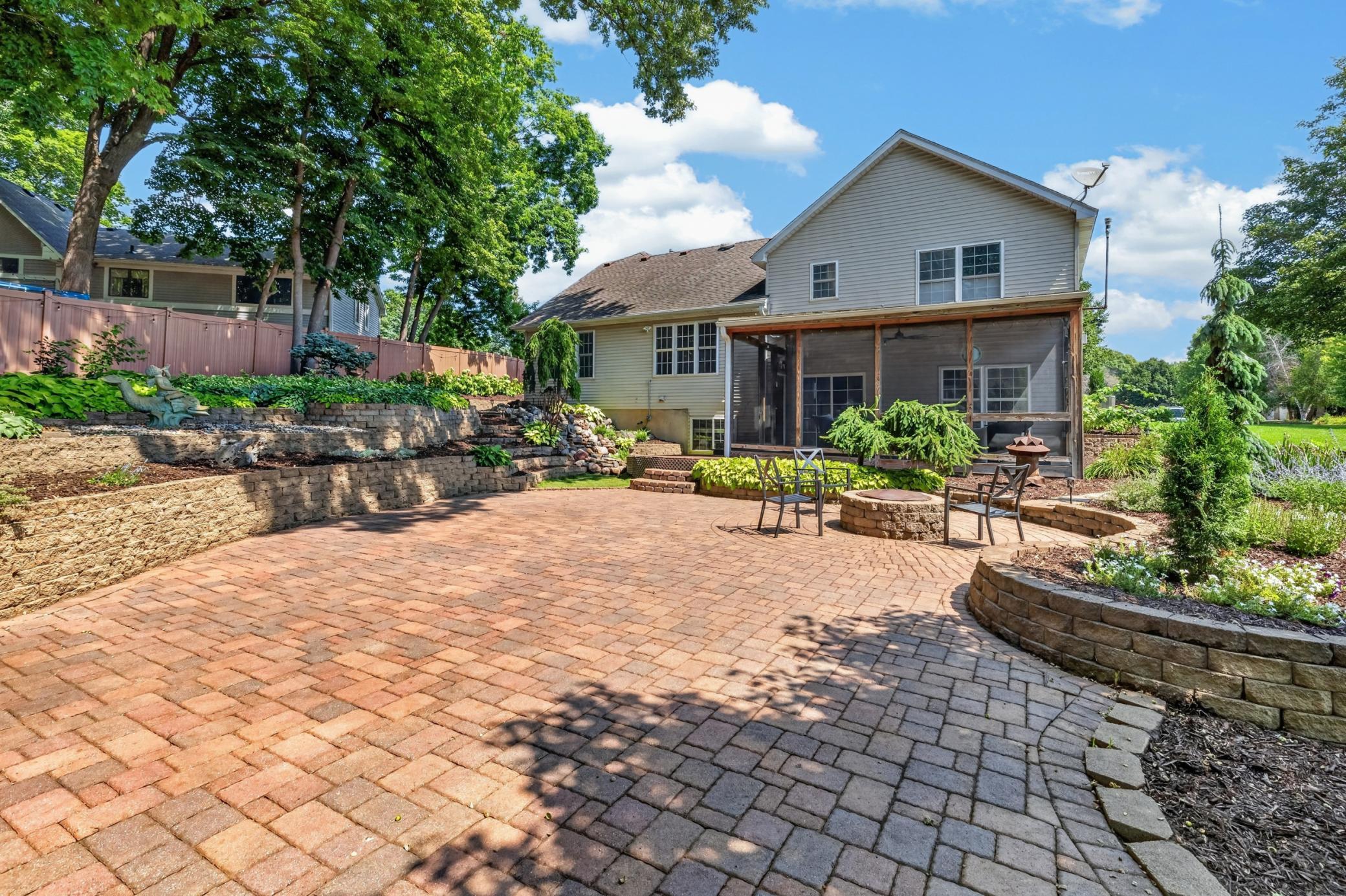 Enjoy a mixture of stone and concrete lined walking paths, tiered perennial gardens, stunning waterfall and a generously sized paver patio with built-in firepit