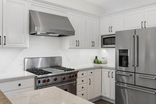 Stainless steel appliances include a Wolf gas range with hood, KitchenAid French door refrigerator, built-in microwave and dishwasher