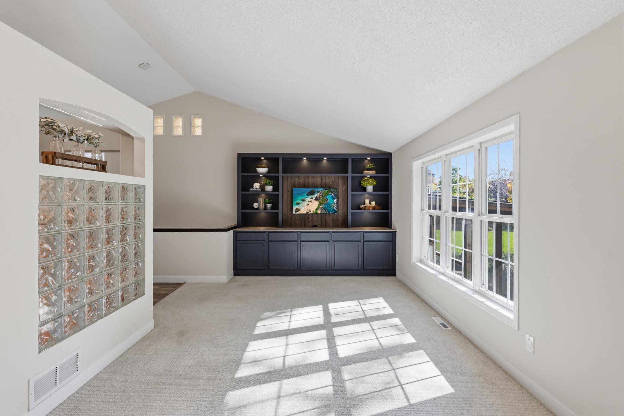 Living Room features built-in entertainment cabinetry that offers storage, display shelving with accent lighting and large wood paneled opening for a modern size TV