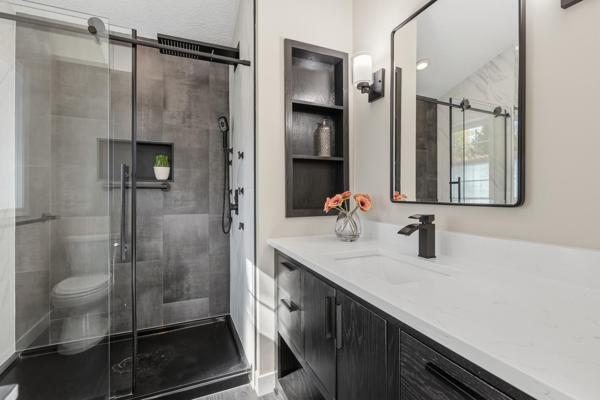 Master 3/4 bathroom features built-in display shelf. The shower features a whole body jet system with additional hand shower and rain shower head, modern tile surround, shampoo niche and frameless glass doors
