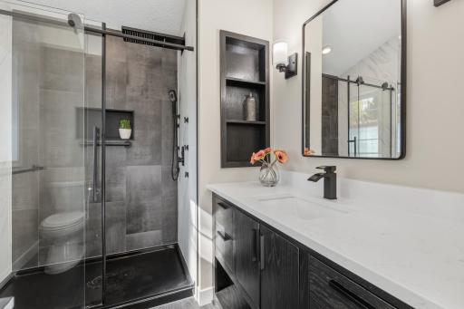 Master 3/4 bathroom features built-in display shelf. The shower features a whole body jet system with additional hand shower and rain shower head, modern tile surround, shampoo niche and frameless glass doors