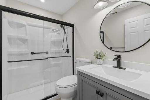 3/4 bathroom features an enameled vanity cabinet and a generously sized shower that offers glass doors