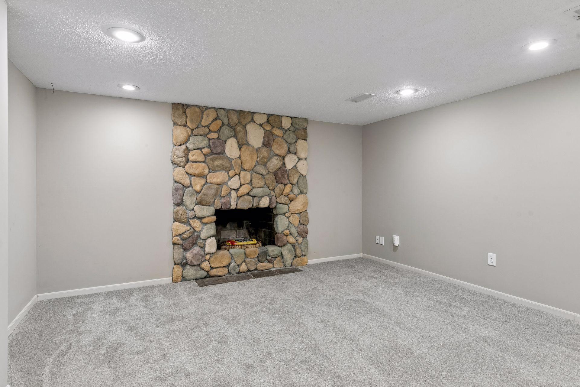 Finished basement with floor to ceiling stone wood burning fireplace. New paint on the ceiling.