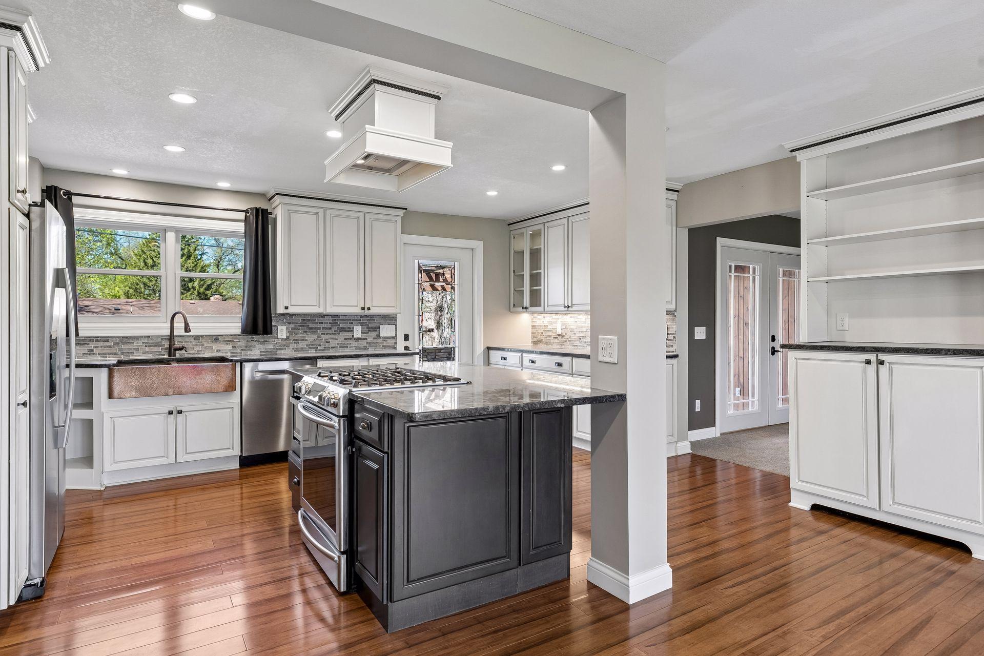 Modern, farmhouse inspired kitchen with large center island, custom cabinetry, stainless appliances, and apron sink.