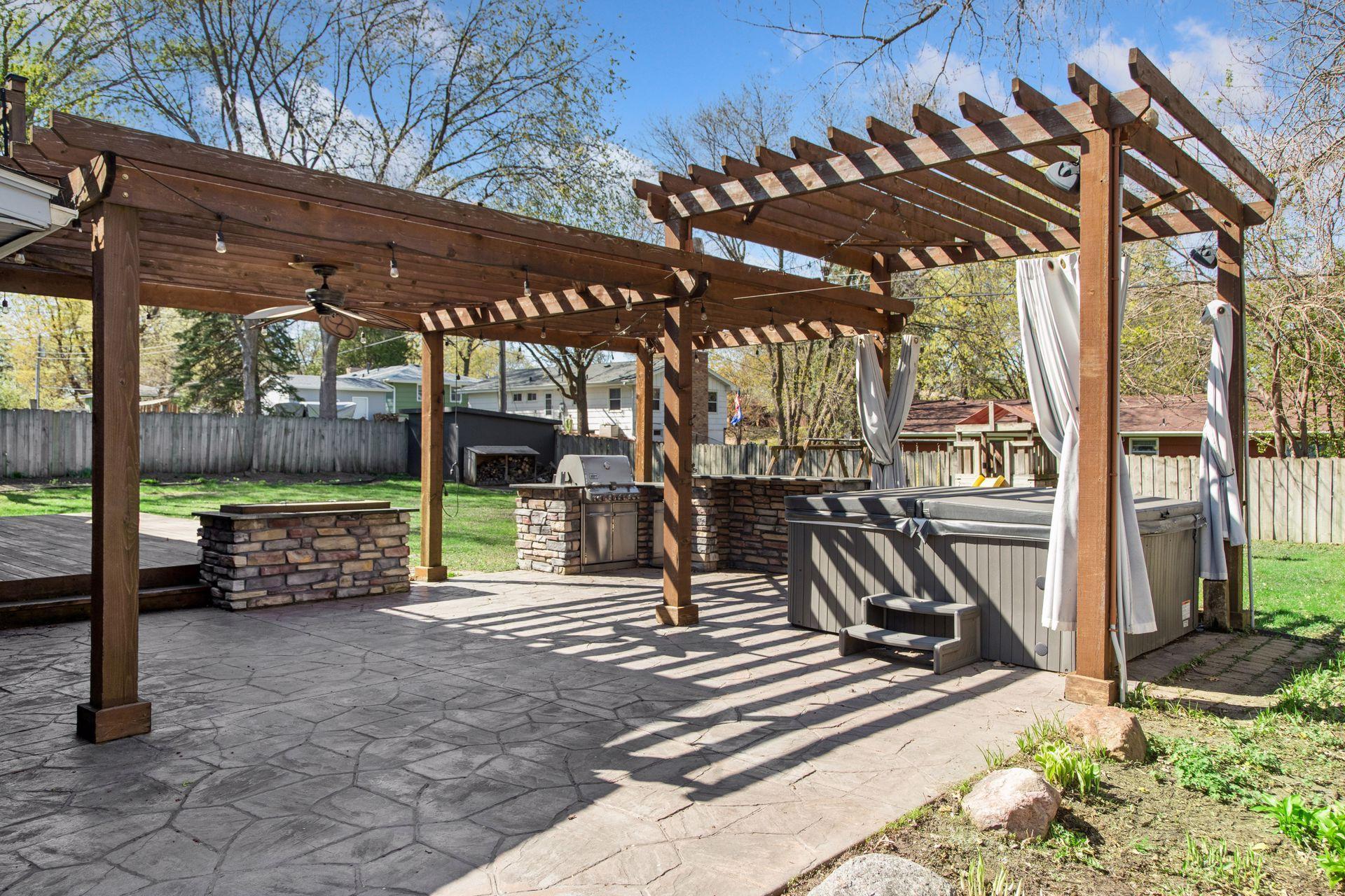 Elevate your outdoor living experience with this dream backyard - hot tub, outdoor kitchen with built-in gas grill and fire pit, 2-tier pergola, stamped concrete patio and large deck.