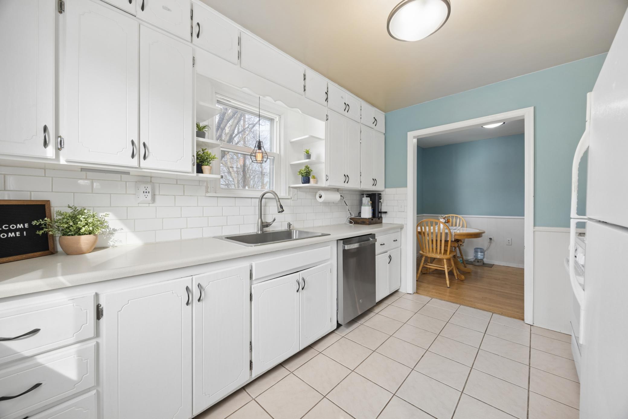 Kitchen features loads of cabinetry, tile backsplash, tile flooring, new SS sink, and a convenient kitchen window for backyard views!