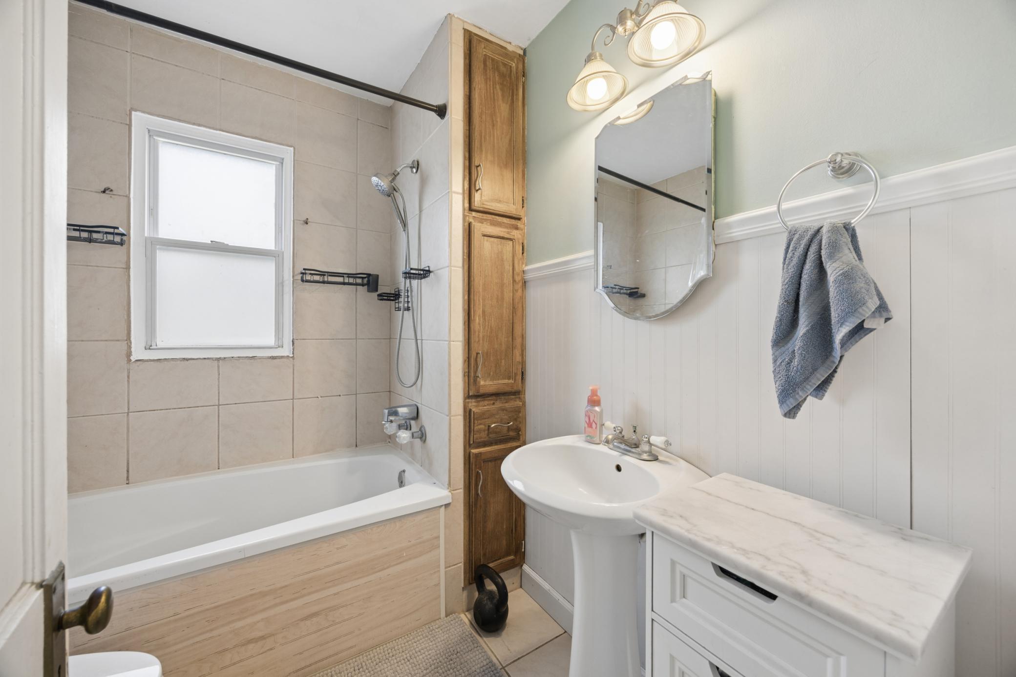 Bathroom features large tub w/tile surround, charming pedestal sink, and tile floors