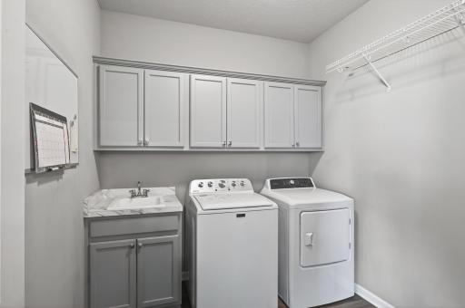 Steps away from the primary suite is this separate laundry room with sink, newer washer, dryer, and upper cabinetry. All living on the main-level.