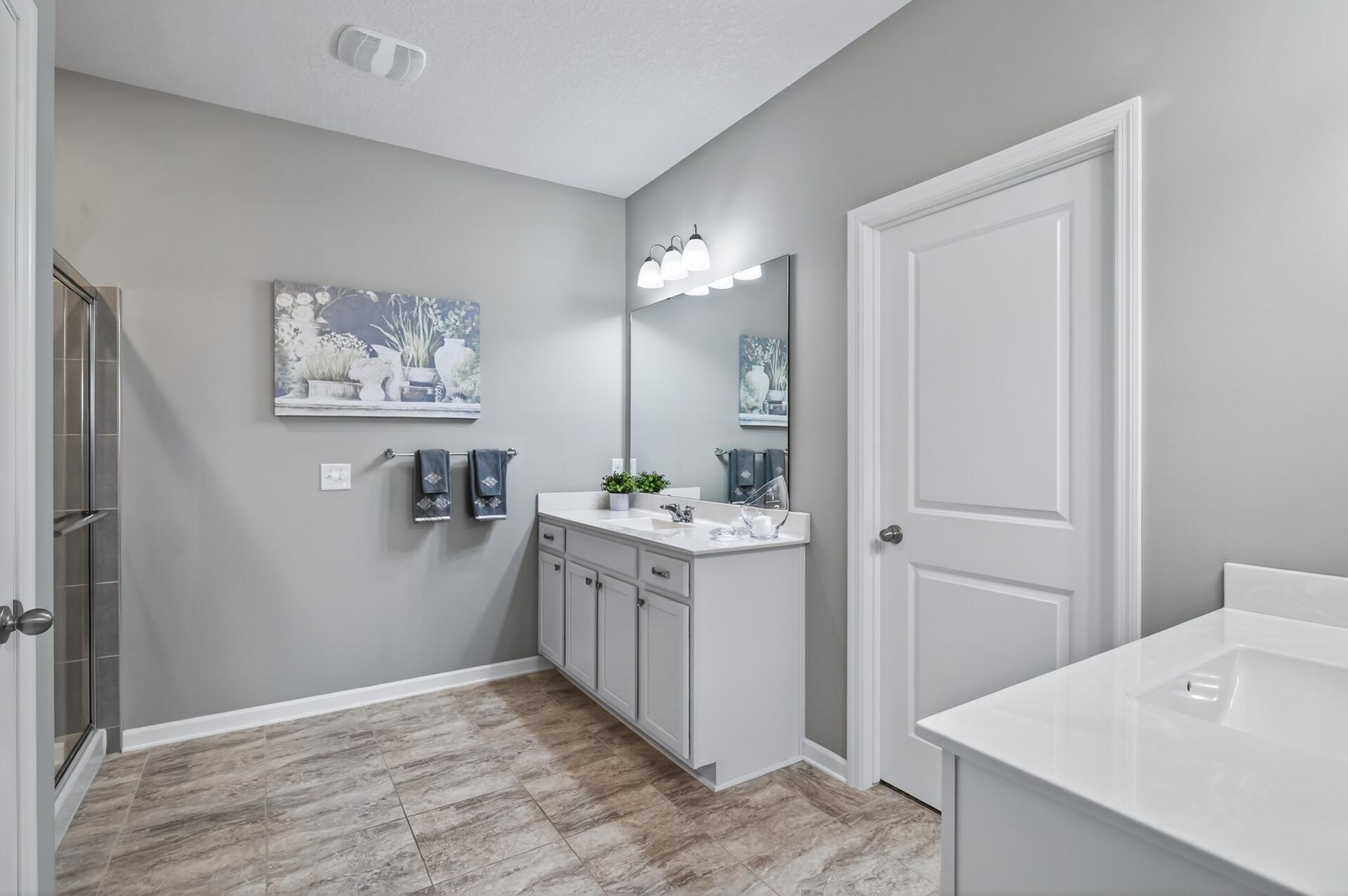 Primary suite 3/4 bath with dual vanities and walk-in closet.
