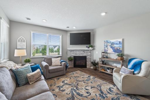 Spacious living room with corner gas fireplace with brick surround and wood mantle.