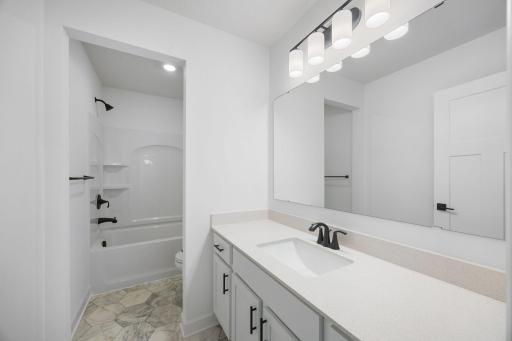 This full bathroom features a wide single vanity and shower-tub combination.