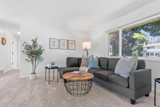 Sun-filled living room with large front windows, fresh carpet (2025), and neutral finishes â perfect for relaxing or entertaining.