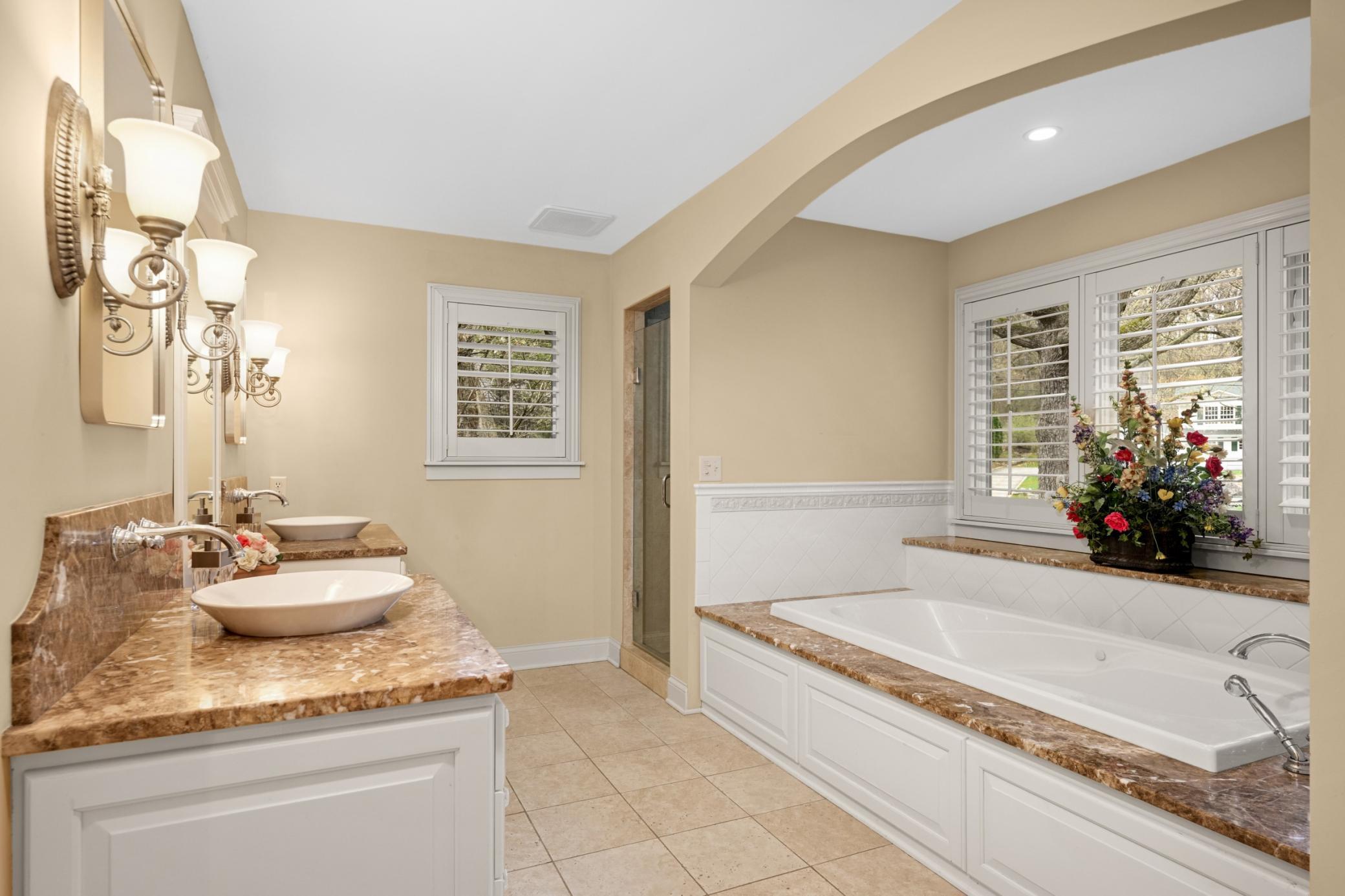 To the right is the primary bath with double vanities, jetted tub, separate shower, and heated floors
