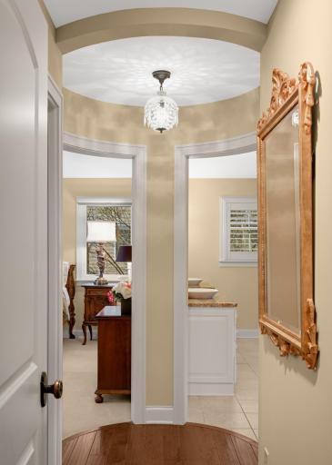A hallway to the vaulted primary suite ends in a curved wall flanked by two doorways
