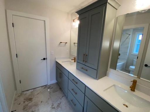 Large Jack-n-Jill bathroom with double sinks, cabinet linen cabinet, and separate door to tub/toilet.