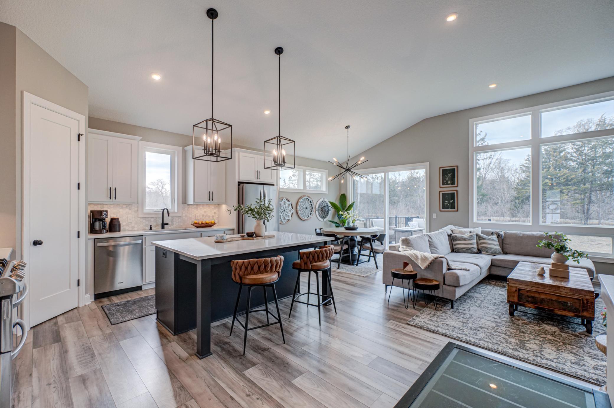The stunning kitchen features stainless steel appliances, a center island, and ample cabinetry, flowing seamlessly into the dining area with access to a maintenance-free walkout deck, perfect for indoor/outdoor living.